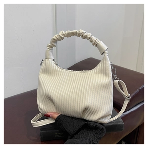Detailed view of off-white pleated handbag with ruched handle and silver hardware