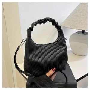 Detailed view of black pleated texture handbag with scrunchie handle and silver hardware