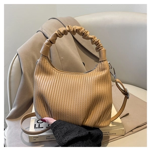 Macro detail of caramel ribbed faux leather bag with ruched handle and sleek zipper closure