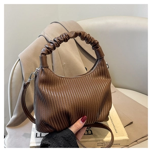 Close-up of brown pleated shoulder bag with scrunchie handle on beige blazer