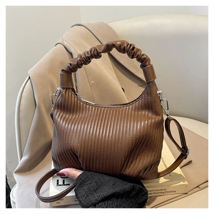 Detail of dark brown pleated texture and silver metal D-ring on a French style handbag