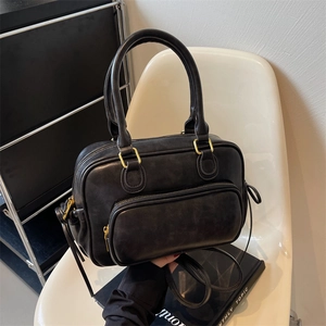 Retro black faux leather shoulder bag with large capacity and double handles on a white chair