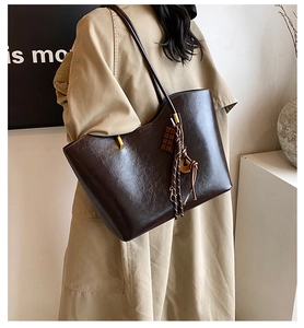 Détail d'un grand sac cabas en cuir marron foncé porté par un mannequin à l'épaule