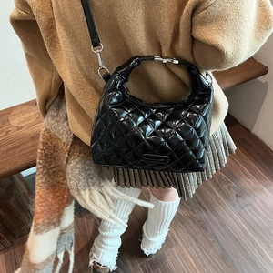 Glossy black quilted shoulder bag with adjustable strap in an autumn lifestyle setting