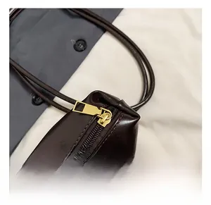 Gros plan sur la fermeture éclair dorée du sac cabas en cuir marron foncé au style rétro