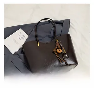 Détail du sac cabas en cuir brillant marron foncé avec pendentif anneau en bois vintage