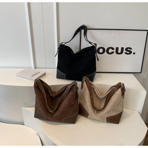 Close-up of large suede hobo tote bags in black, dark brown, and beige with contrast stitching