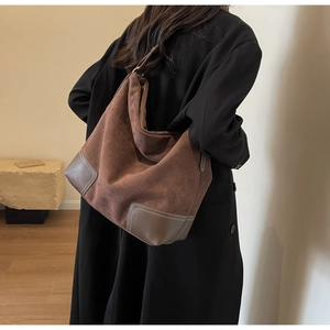 Detail of dark brown suede hobo bag featuring leather patchwork and white contrast stitching
