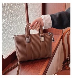 Detailed view of dark brown striped leather texture and silver metallic hardware on bag
