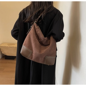 Detail of vintage brown suede hobo bag with leather corner patches and contrast stitching
