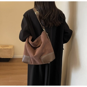 Detail of suede shoulder bag featuring contrast stitching and reinforced leather base