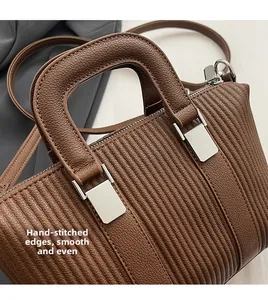 Detail of hand-stitched edging and smooth lychee texture on brown leather handbag