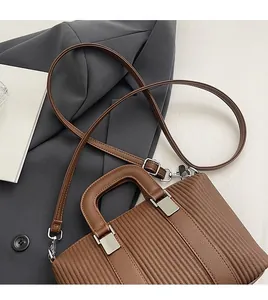 Detail of brown pleated faux leather tote bag with silver buckle on grey blazer