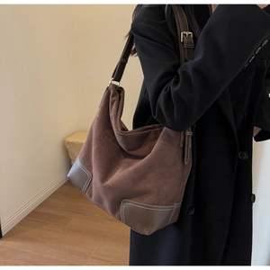Detail view of large brown suede hobo bag featuring leather patches and white stitching