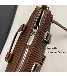 Detail view of smooth silver metal zipper and brown pleated texture on a fashion handbag