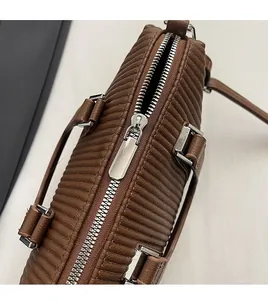 Detail view of smooth silver metal zipper and brown pleated texture on a fashion handbag
