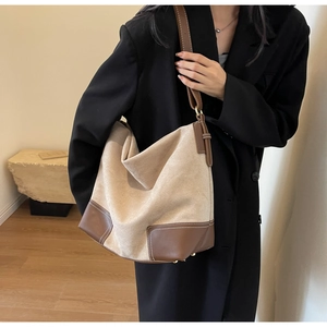 Detail of oatmeal suede tote bag showing contrast brown leather stitching and adjustable strap