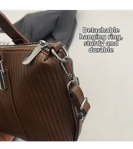 Detail of brown embossed textured handbag showing silver hardware and detachable strap