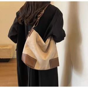 Side view of a vintage beige suede hobo tote bag with brown leather trim and shoulder strap