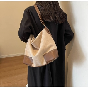 Detail of vintage suede tote bag showing leather stitching and beige textured fabric