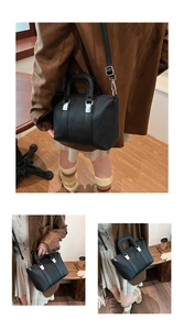 Detail view of black pleated tote bag showing handle, silver hardware and crossbody strap