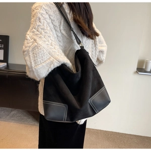 Detail of large black suede tote bag showing leather corner patches and contrast stitching