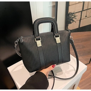 Detail of black pebbled leather handbag with vertical stitching and silver hardware