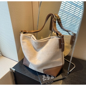 Detail view of large faux suede tote bag with contrast stitching and adjustable leather strap