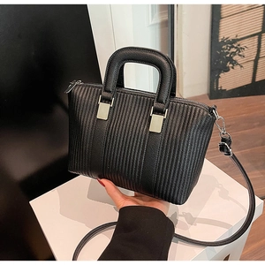 Detailed view of black pleated crossbody bucket bag with silver hardware on white stand