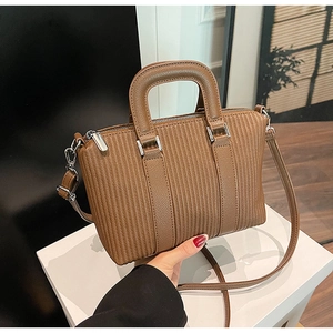 Detailed view of the vertical pleated texture and silver hardware on a brown bucket bag