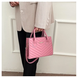 Close-up of pink quilted crossbody bag with golden logo and detachable strap on a model