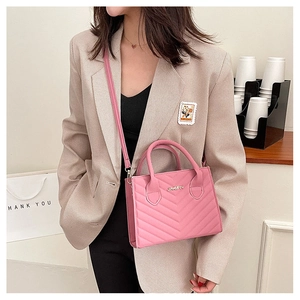 Detail of pink crossbody bag with V-shaped quilted stitching and metallic JINGPIN logo
