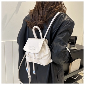 Detail of a beige mini backpack showing drawstring closure and brand logo on the flap