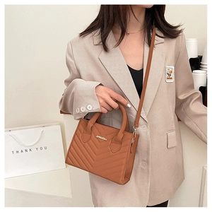 Brown quilted leather crossbody bag featuring JINGPIN metal logo plaque in a cafe setting