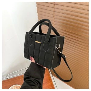 Detail of black quilted crossbody bag with gold JINGPIN logo and textured finish