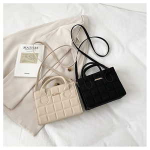 Close-up of quilted pattern bags in black and beige with elegant golden logo detail