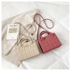 Detail of cream and dusty pink quilted tote bags with JINGPIN logo and shoulder straps