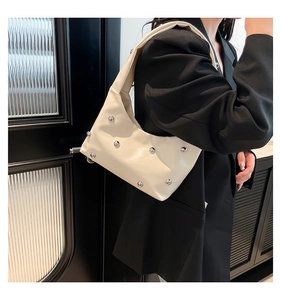 Detail van crème hobo tas met zilveren klinknagels en minimalistisch schouderontwerp