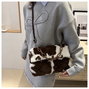 Détail du sac bandoulière en peluche motif vache avec chaîne acrylique et texture douce