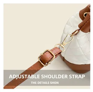 Detail of adjustable brown leather strap and gold-tone hardware on a quilted bucket bag