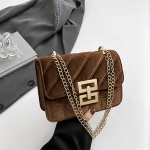 Nahaufnahme der gesteppten braunen Wildledertasche mit Goldkette und geometrischer Schnalle