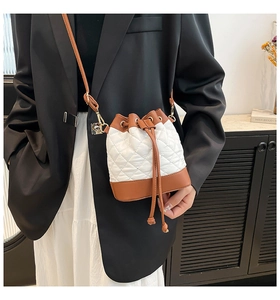 On-body shot of a quilted drawstring bucket bag featuring white and brown contrast design
