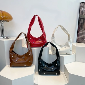 Leren schoudertassen met klinknagels in vier kleuren op een modern display