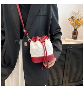 Detail of a white quilted bucket bag with red trim and golden metal hardware