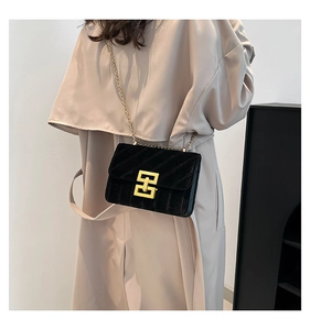 Detail of black quilted velvet crossbody bag featuring golden buckle and chain strap
