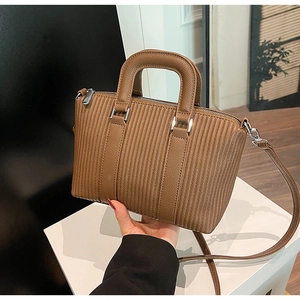 Detail of a brown bucket bag showing fine vertical pleats and round double handles