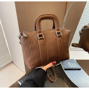 Close-up of brown tote bag with vertical embossed texture and silver hardware details