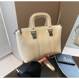 Detailed close-up of cream textured bucket bag with silver hardware and dual zippers