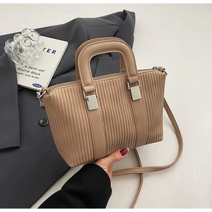 Detailed view of camel pleated leather bucket bag on a professional grey blazer background