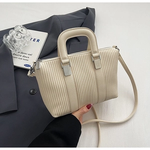 Detailed view of cream textured bucket bag with vertical quilting and silver hardware
